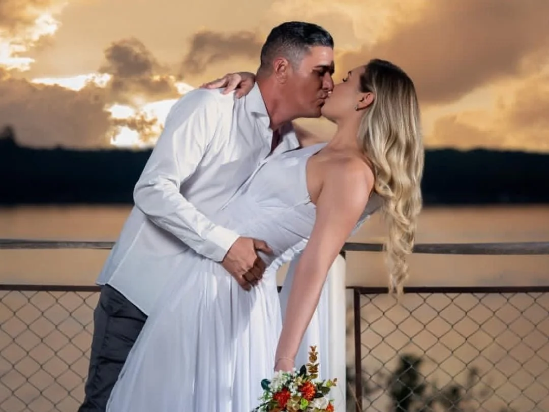 Casal de noivos se beijando ao pôr do sol